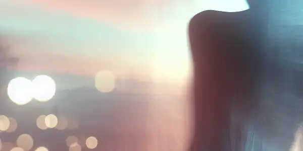 A semi-transparent silhouette of a woman turning away, evoking melancholy and anticipation amidst a dreamy, blurred background.